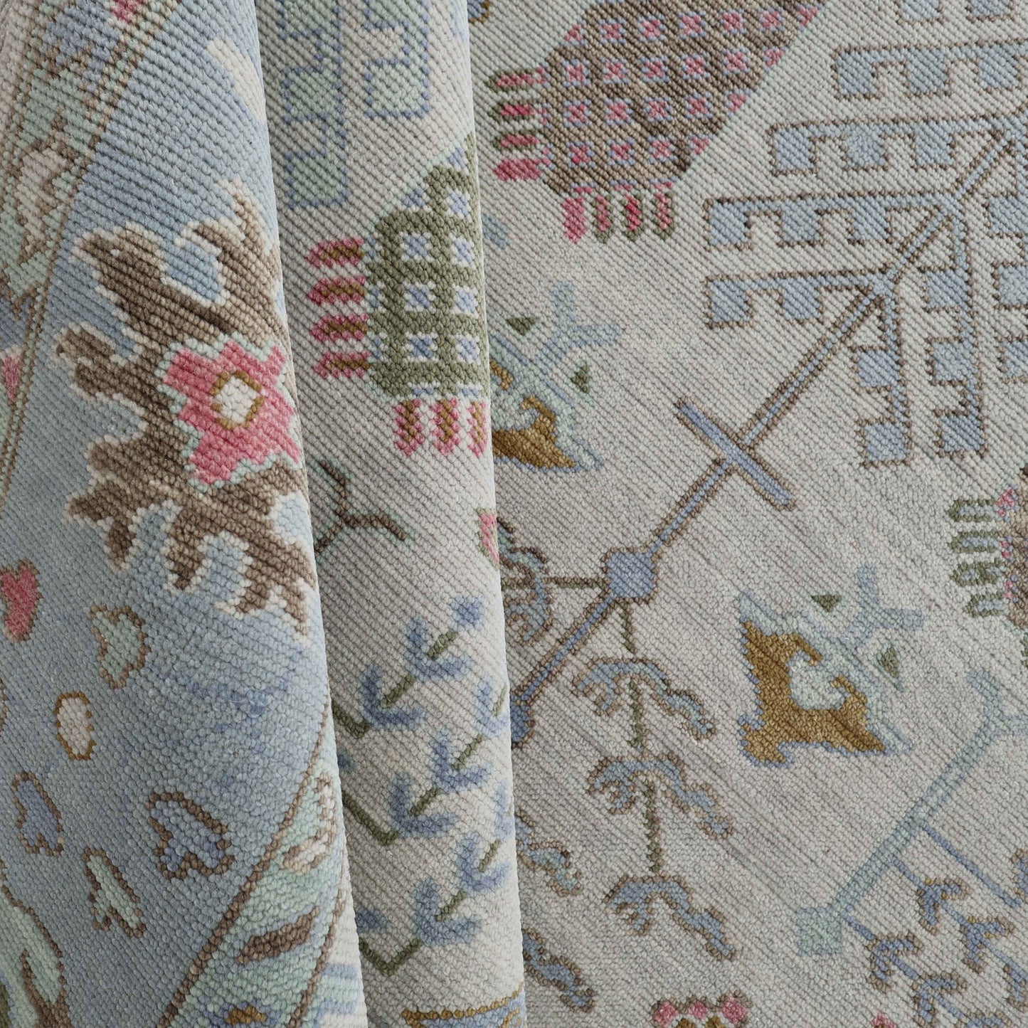 A close-up view of a patterned fabric with floral and geometric designs in a variety of colors including blue, beige, pink, and green.