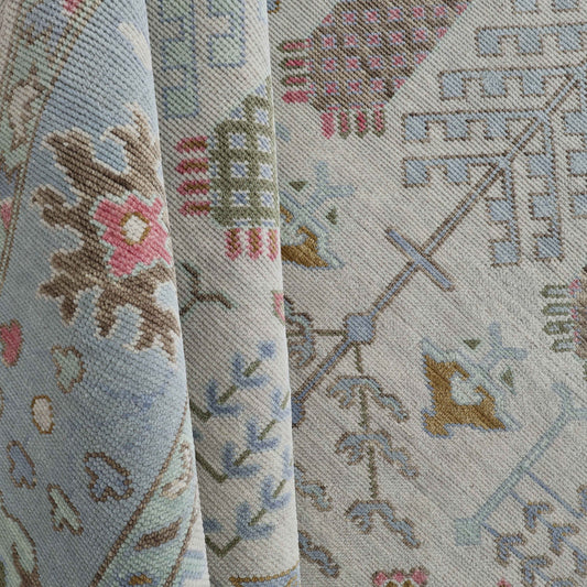 A close-up view of a patterned fabric with floral and geometric designs in a variety of colors including blue, beige, pink, and green.