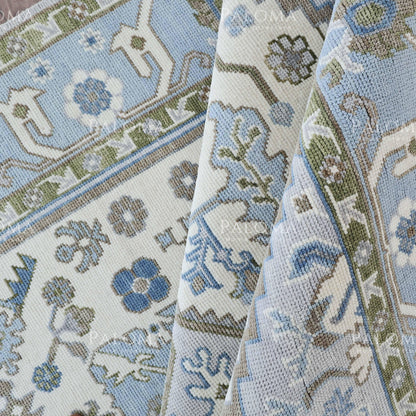 Close-up of a patterned rug with blue, soft tones, and green.