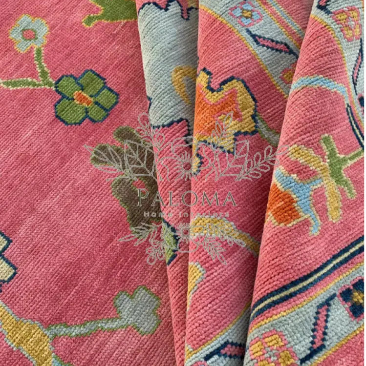 A close-up view of a pink area rug with a floral pattern, featuring shades of blue, green, and beige.