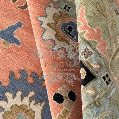 Close-up view of a handmade rug with floral patterns in a mix of coral, navy, and other colors.