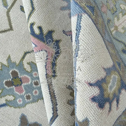 Close-up view of a handmade rug with floral patterns in beige, blue, and pink colors