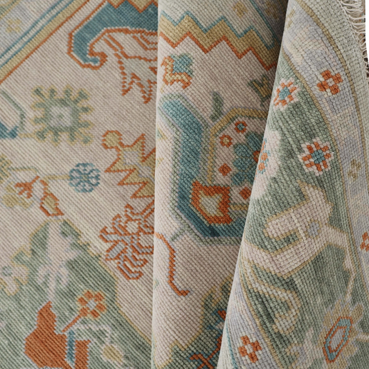 Close-up view of a handmade rug with floral and geometric patterns in beige, blue, green, and orange colors