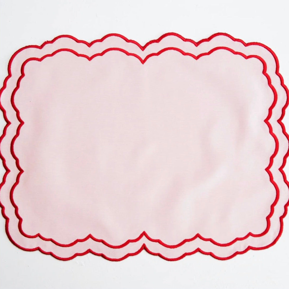 Pink fabric with red scalloped edge on a white background