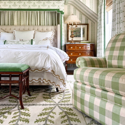 Green and white checkered chair in a bedroom with patterned wallpaper and furniture.