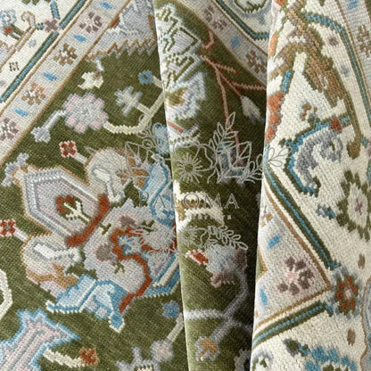 Close-up view of a moss green rug with detailed floral patterns.