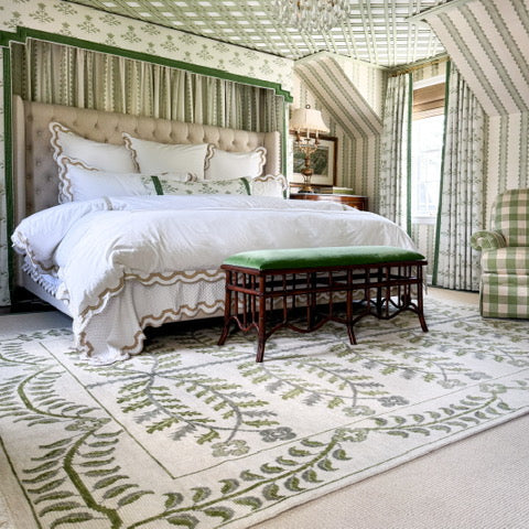 Decorative bedroom with a bed, bench, and armchair, featuring green and white color scheme.