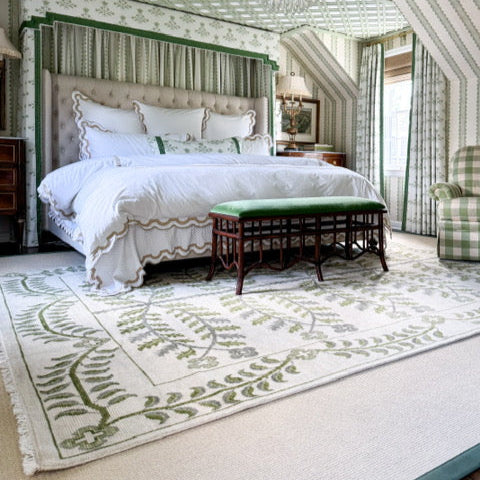 Luxurious bedroom with a large bed, green bench, and patterned rug.