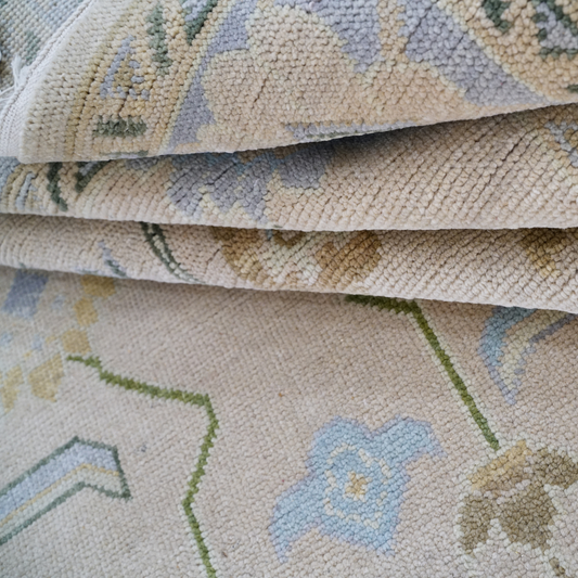 Close-up of a textured fabric with floral patterns in beige, blue, and green.