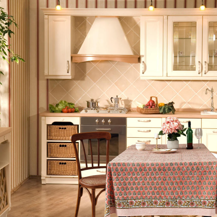 Kitchen interior with wooden cabinets, a stove, and a table with a patterned tablecloth.