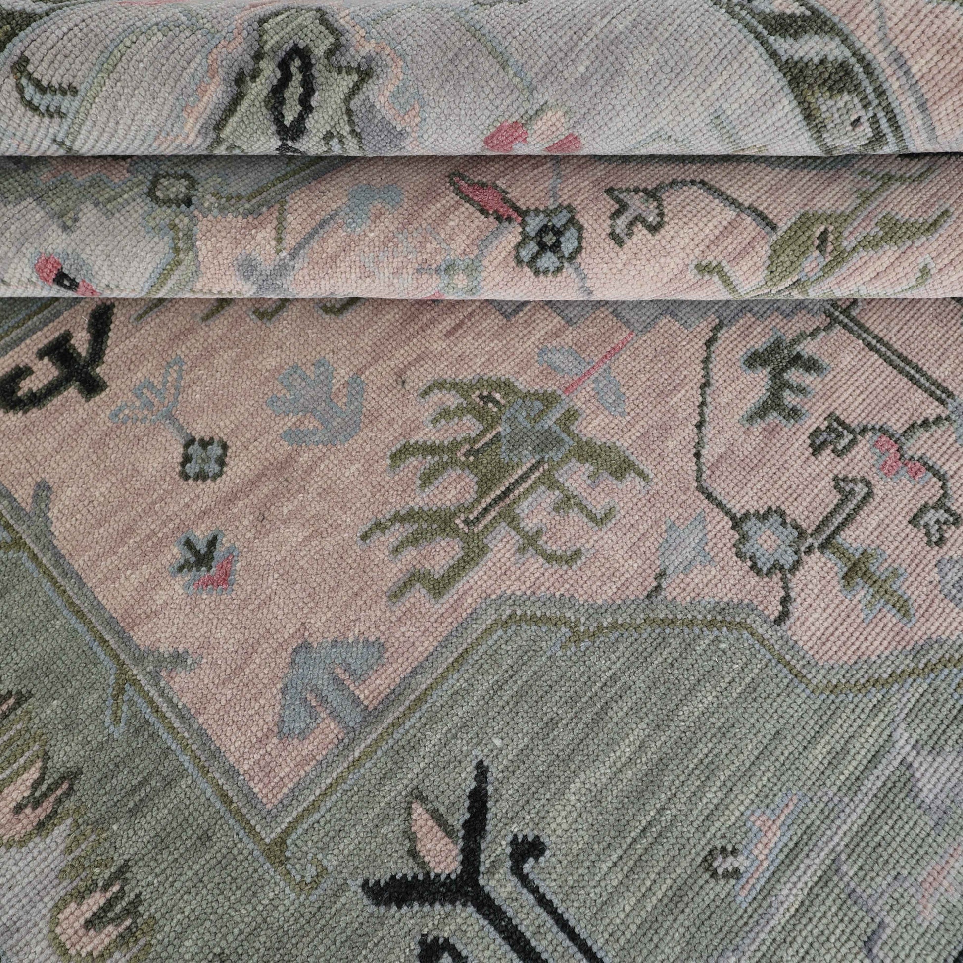 Close-up view of a handmade rug with floral patterns in green, beige, and other colors.