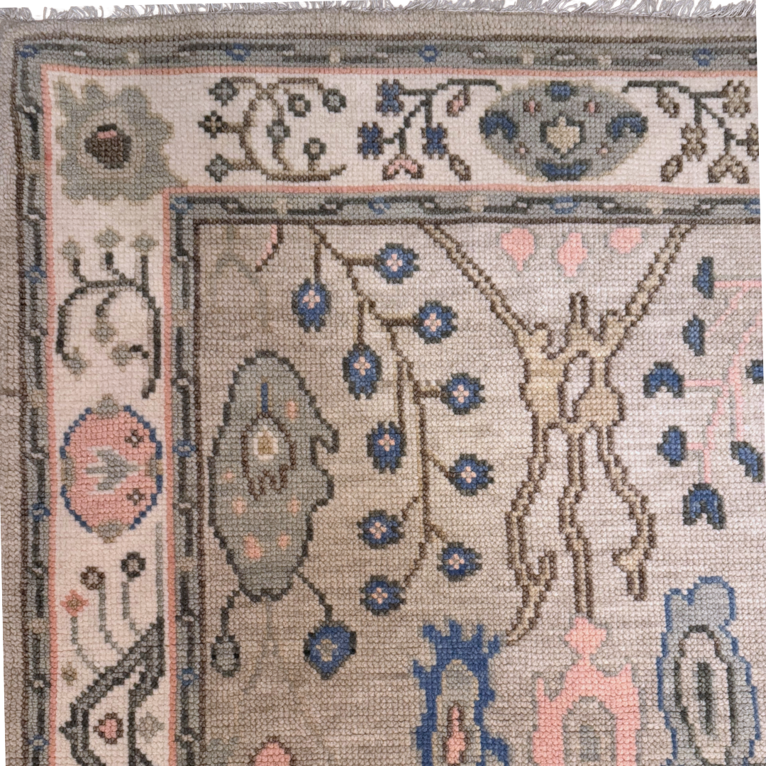 Decorative rug with intricate patterns of blue and soft pink on a slate green field. 