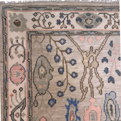 Decorative rug with intricate patterns of blue and soft pink on a slate green field. 