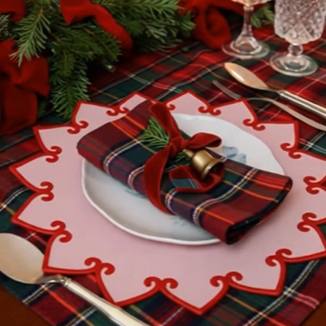 Christmas-themed table setting with plaid napkin, red ribbon, and decorative plate on a plaid tablecloth.